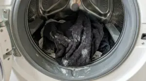 Cestello della lavatrice con asciugamani scuri e residui di detersivo, possibile causa di bucato duro